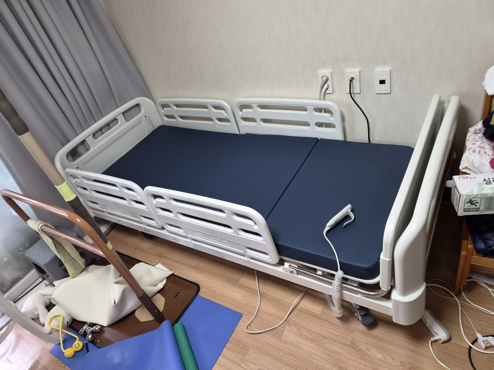 동래 재가복지와 함께 안내하는 복지용구 참고사진 - 방 벽면을 따라 설치된 전동침대와 리모컨